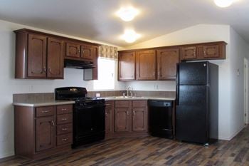A kitchen with dark wood cabinets and black appliances